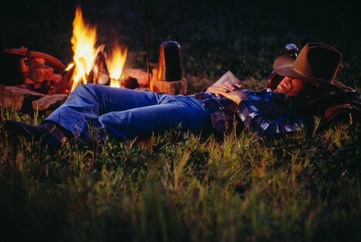 Cowboy sleeping next to campfire with Canvas Cutter Bedroll