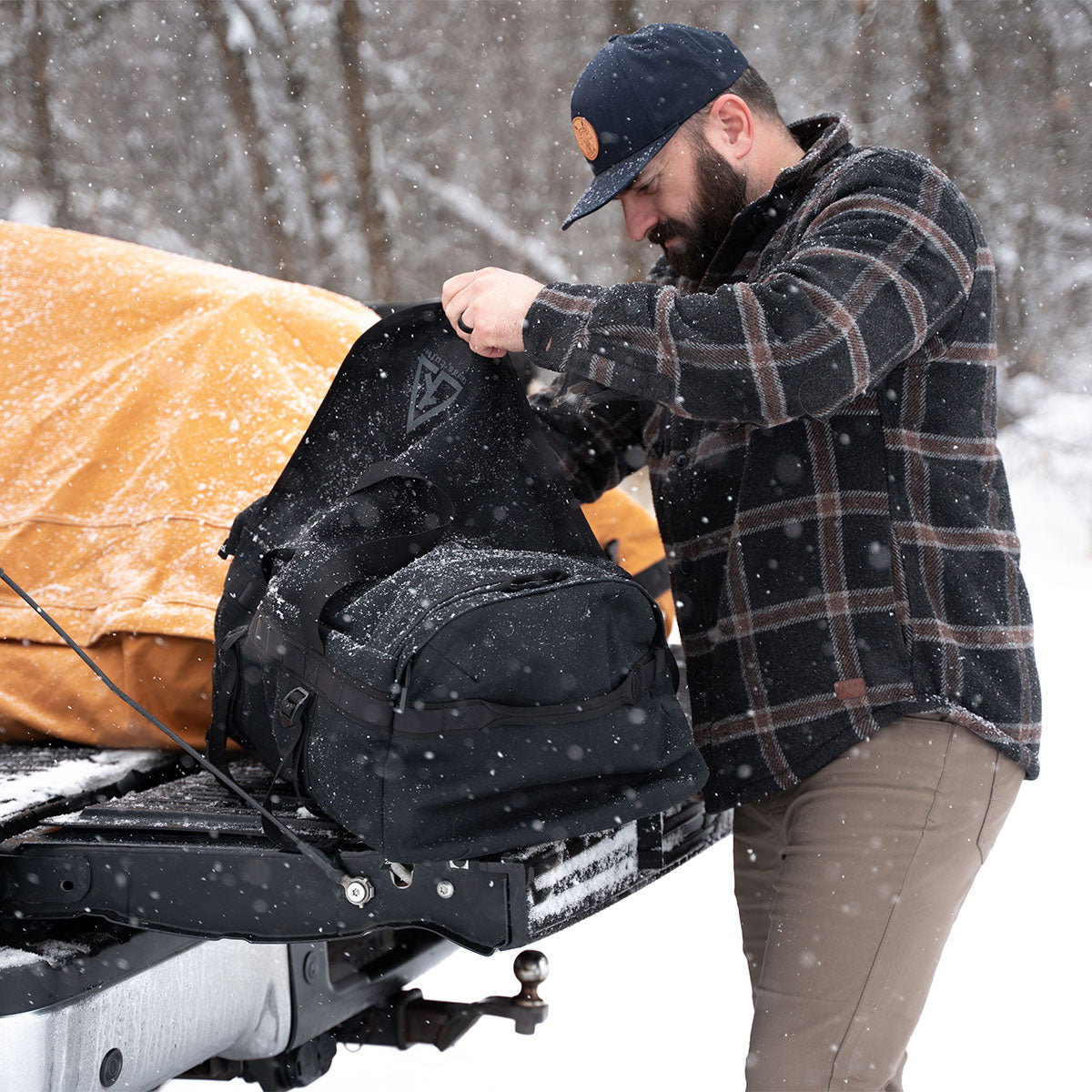 Burro duffel used outdoors in snowy conditions next to a truck