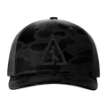 Front view of the Canvas Cutter Darkwater Hat featuring a black camouflage cap with a logo on a blackout five panel trucker design