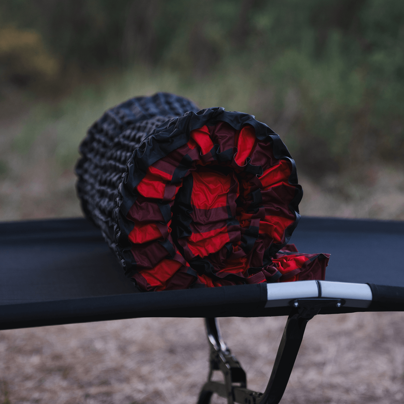 Bedrock Pad rolled up and resting on a cot showing compact packed size for travel
