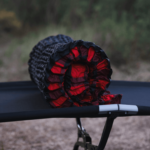 Bedrock Pad rolled up and resting on a cot showing compact packed size for travel