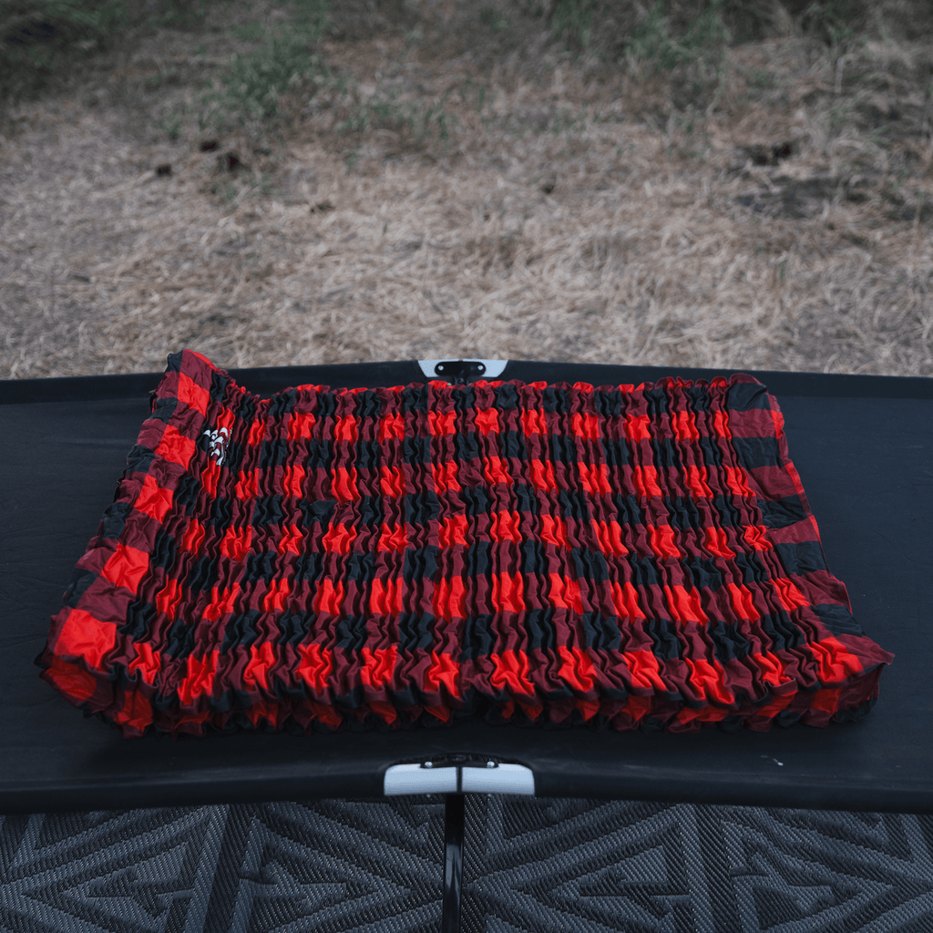 Bedrock Pad unrolled on a cot before inflation showing fit and layout inside a sleep system